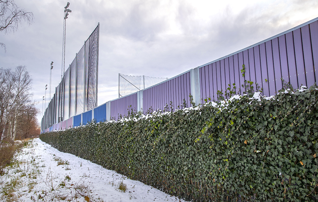 På Mälarhöjdens idrottsplats finns ett staket med grönska på.